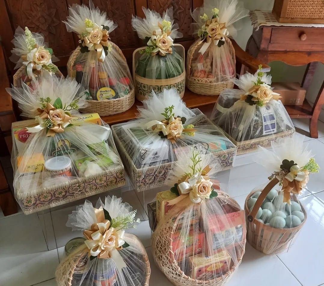 Assortment of tulle-wrapped gift hampers in woven baskets with gold ribbon roses