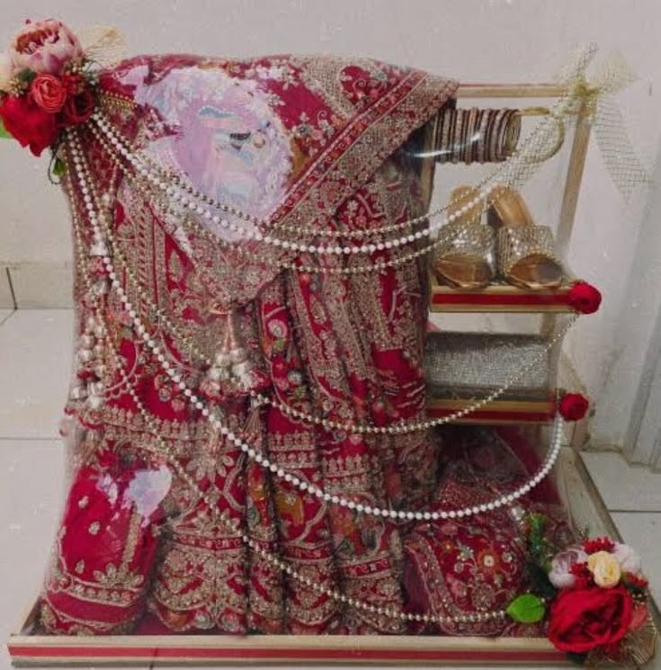 Bridal lehenga gift wrapped on a stand with pearls and roses